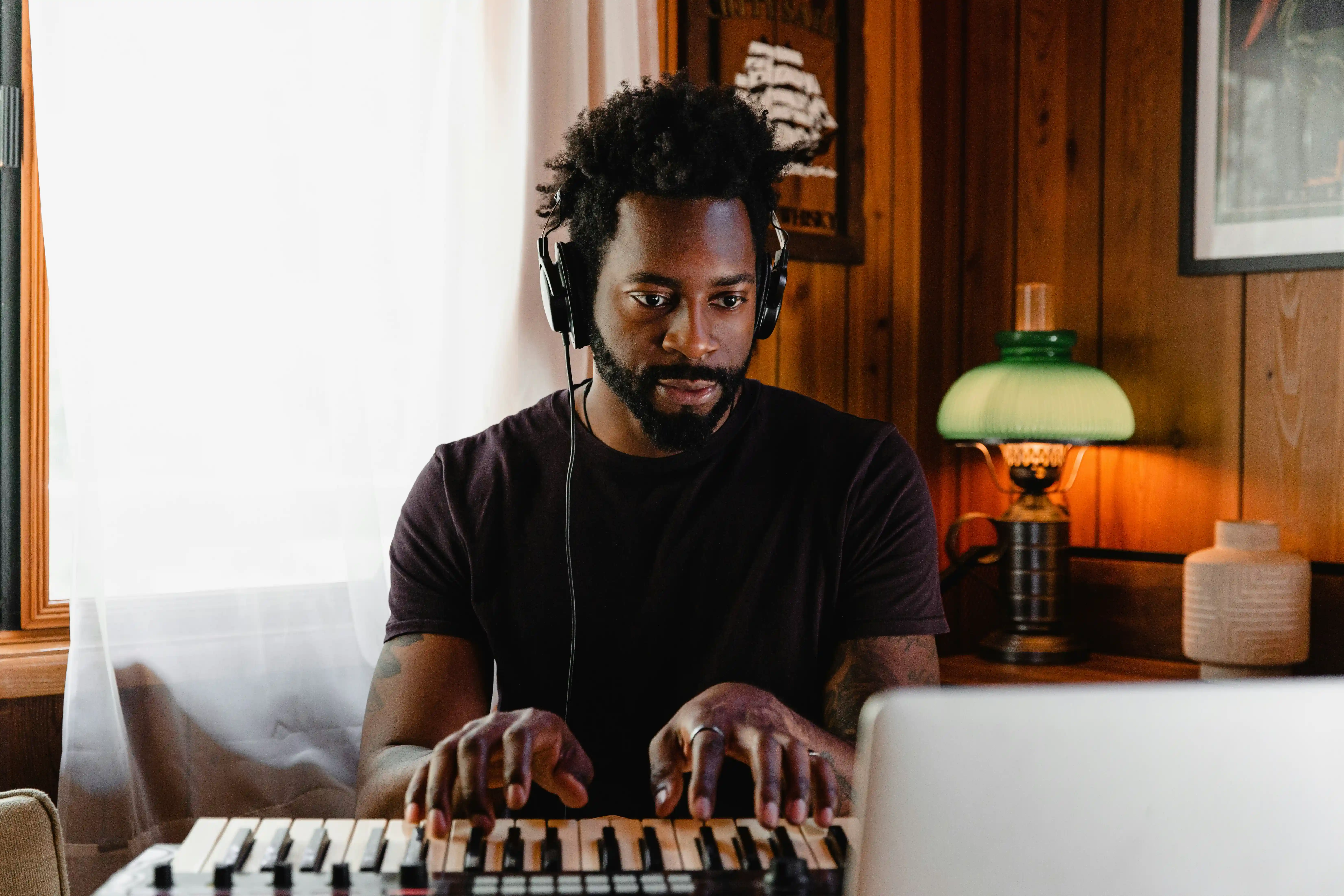 A musician recording on a keyboard in front of a laptop
